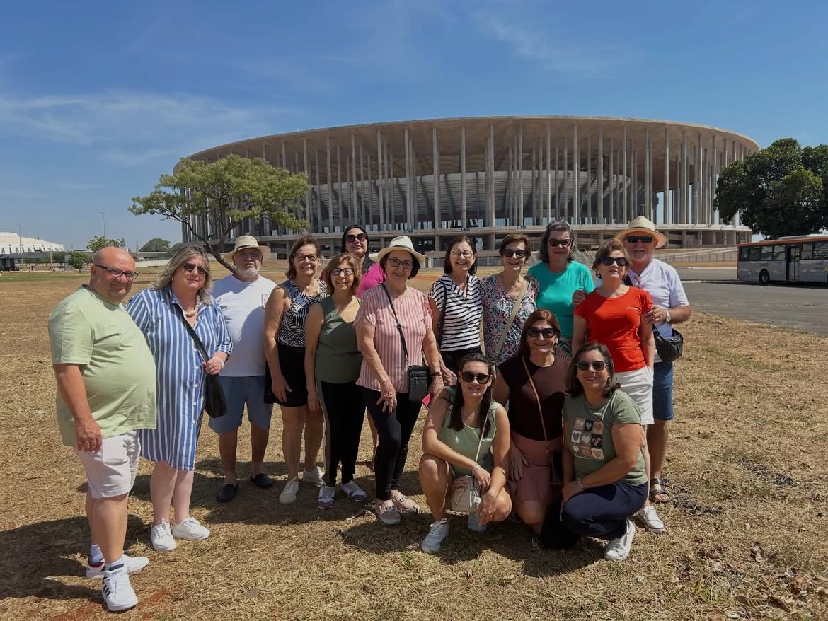 Grupo de viajantes posando em frente ao Estádio Mané Garrincha, em Brasília